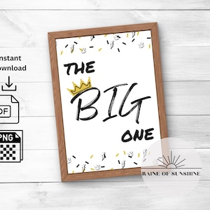 Può includere: Un cartello stampabile con una corona dorata e il testo "THE BIG ONE" in scrittura nera. Lo sfondo è bianco con un motivo di coriandoli composto da corone dorate, fulmini neri e trattini neri.
