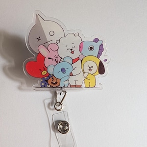 May include: A clear acrylic badge reel featuring a group of colorful cartoon characters. The characters include a gray head with an X and O, a pink heart, a white cloud, a blue koala, a purple horse, a yellow figure, and a brown dog. The reel has a clear plastic strap and a metal clip.
