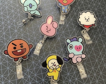 May include: A collection of seven cartoon character badge reels. Each reel features a different character in various colors, including blue, pink, orange, yellow, and red. The reels have a clear plastic retractable cord and a metal clip for attaching to clothing.