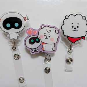 May include: Three cartoon character badge reels. The first is a white robot with a black oval face and blue eyes. The second is a white sheep with a red scarf. The third is a white robot with a black oval face and blue eyes hugging a pink sheep.