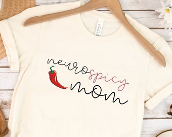 Könnte beinhalten: Ein naturfarbenes T-Shirt mit dem Text "neurospicy mom" und einer roten Chilischote.