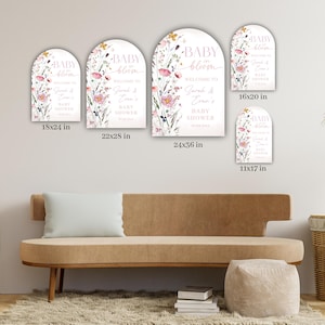 May include: A collection of arched signs with floral designs and the text "BABY bloom WELCOME TO Sarah & Evan's BABY SHOWER". Sizes include 11x17 in, 16x20 in, 18x24 in, 22x28 in, and 24x36 in. The signs are displayed on a wall.