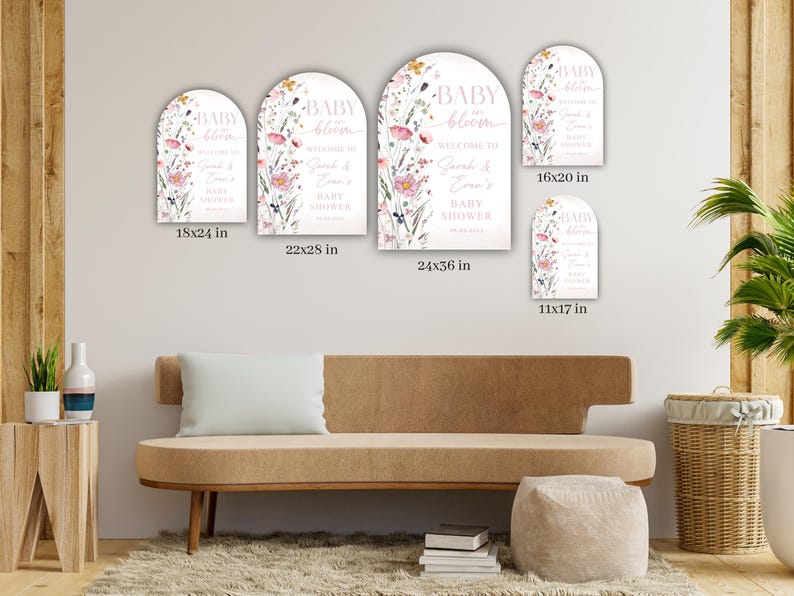May include: A collection of arched signs with floral designs and the text "BABY bloom WELCOME TO Sarah & Evan's BABY SHOWER". Sizes include 11x17 in, 16x20 in, 18x24 in, 22x28 in, and 24x36 in. The signs are displayed on a wall.