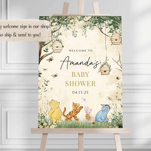 May include: A welcome sign for a baby shower with a Winnie the Pooh theme. The sign features a green and brown woodland background with Winnie the Pooh, Tigger, Piglet, and Eeyore characters. The text on the sign reads "Welcome to Amanda's Baby Shower 04.13.25".