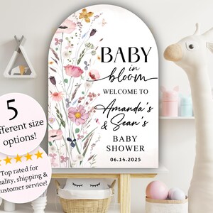 Puede incluir: Un cartel blanco en forma de arco con un dise&ntilde;o floral y el texto "BABY in bloom WELCOME TO Amanda's & Sean's BABY SHOWER 06.14.2025".