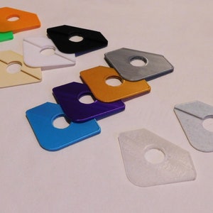 May include: A set of ten plastic corner protectors in various colors, including green, orange, white, cream, black, silver, gold, purple, blue, and light gray. Each protector has a hole in the center.