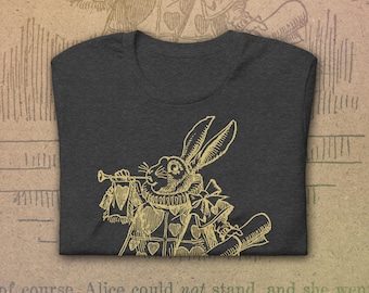 May include: A dark grey t-shirt with a gold illustration of the White Rabbit from Alice in Wonderland playing a trumpet. The rabbit is wearing a waistcoat and a bow tie.