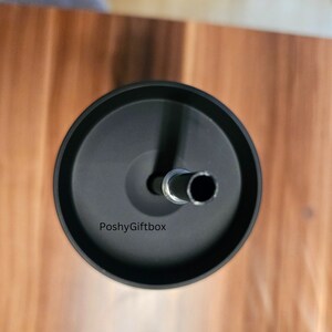 May include: Black stainless steel tumbler with a lid and a straw. The tumbler has the text "PoshyGiftbox" printed on the side.