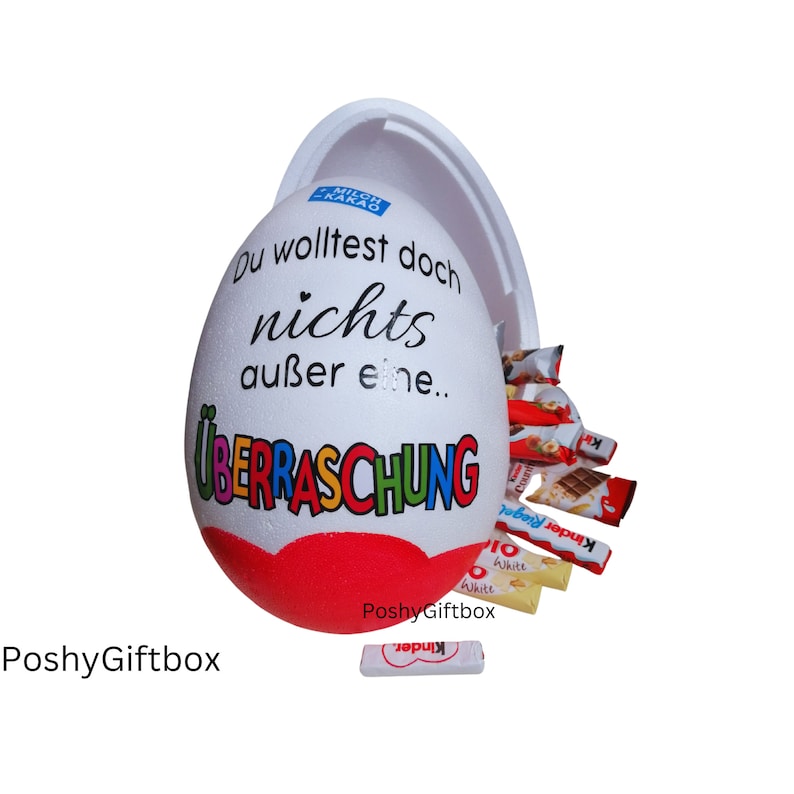 May include: A white plastic egg with a red heart and the text "Du wolltest doch nichts au&szlig;er eine... &Uuml;BERRASCHUNG" in rainbow colors. The egg is open and filled with various chocolate bars and candies.