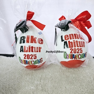 May include: Two white graduation balloons with red, black, and colorful accents. The balloons are decorated with the text "Rike Abitur 2025" and "Lenn Abitur 2025" with the word "&Uuml;berraschung" underneath each name.