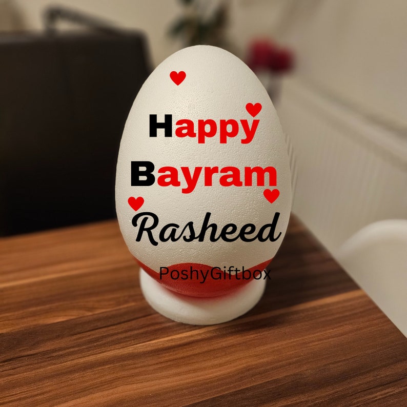 May include: White styrofoam egg with red hearts and black text that reads "Happy Bayram Rasheed" and "PoshyGiftbox".