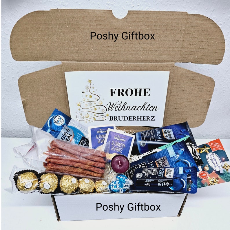 May include: A brown cardboard gift box with the words "Poshy Giftbox" printed on the top. The box is open and filled with various items, including a candle, chocolate, snacks, and toiletries. A white card with the words "FROHE WEIHNACHTEN BRUDERHERZ" is visible inside the box.
