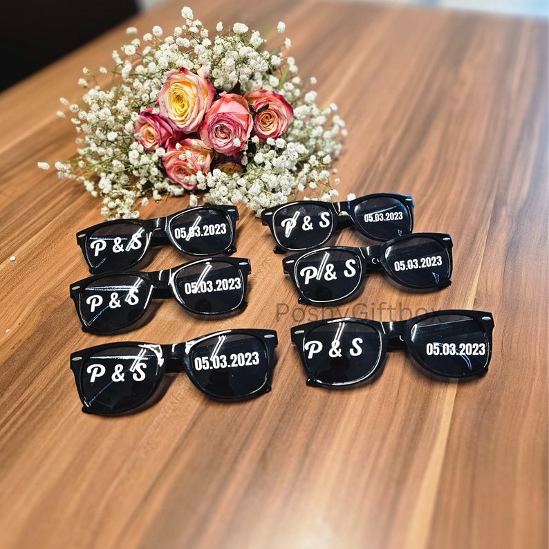 May include: Eight black plastic sunglasses with white text that reads "P&S" and "05.03.2023".