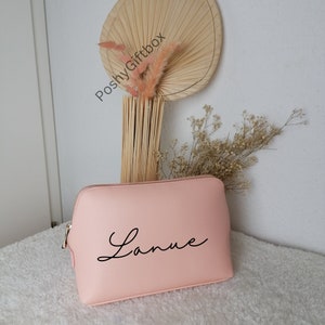 May include: A light pink zippered makeup bag with the name "Lanie" written in black cursive script.