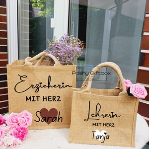 May include: Two brown burlap tote bags with black text and a heart design. The first bag says "Erzieherin mit Herz Sarah" and the second bag says "Lehrerin mit Herz Tanja".