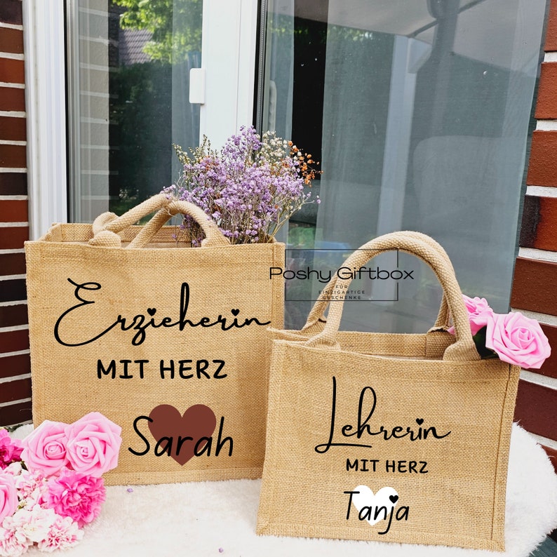 May include: Two brown burlap tote bags with black text and a heart design. The first bag says "Erzieherin mit Herz Sarah" and the second bag says "Lehrerin mit Herz Tanja".