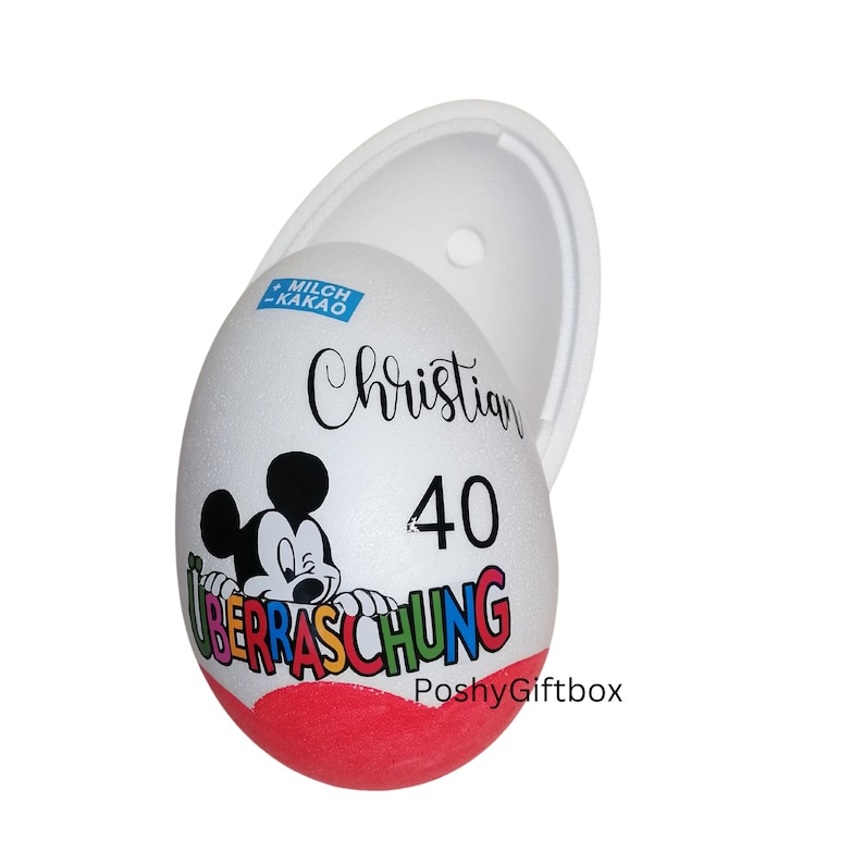 May include: A white egg-shaped container with a red and white Mickey Mouse design. The container has the text "Christian 40 &Uuml;berraschung" and "PoshyGiftbox" printed on it.