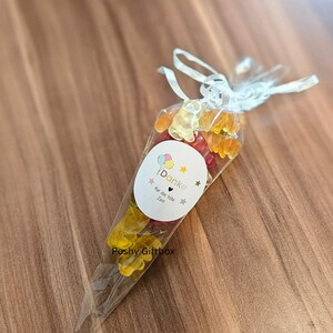 May include: A clear plastic cone filled with colorful gummy bears. The cone has a white label with the text "Danke f&uuml;r die tolle Zeit" and a small heart.