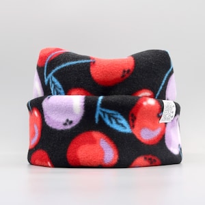 May include: Black fleece headband with a cherry print. The headband has a white label with the text "Made in China" on it.