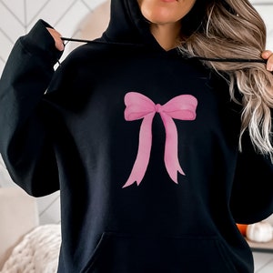 May include: Black hoodie with a pink bow design on the front.