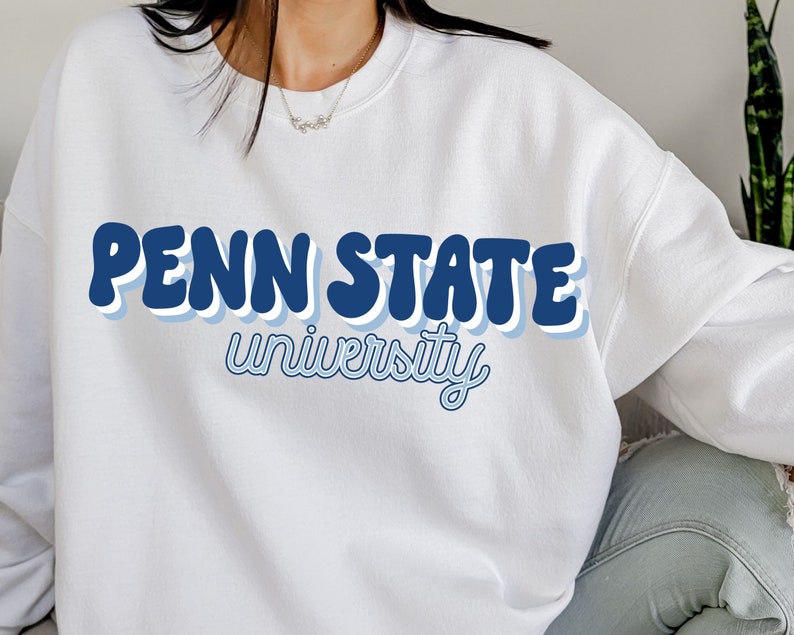 May include: White sweatshirt with a blue and white retro-style graphic that says "Penn State University".