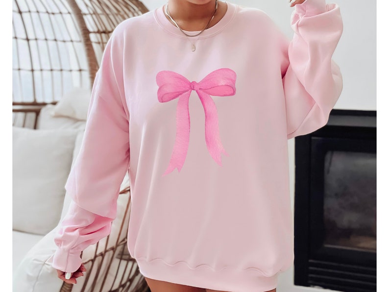 May include: A pink sweatshirt with a large pink watercolor bow printed on the front.