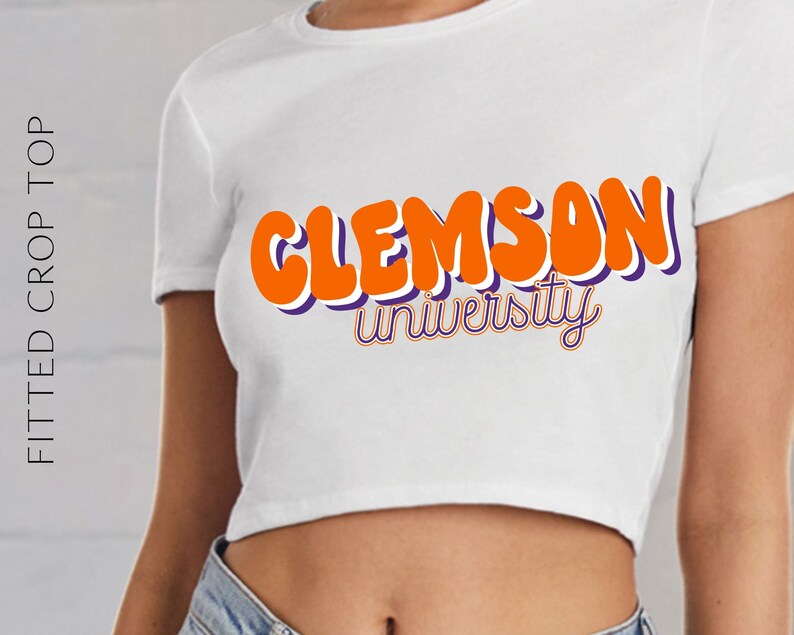 May include: White fitted crop top with the text "Clemson University" in orange and purple lettering.