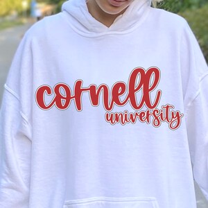 May include: White hooded sweatshirt with a red and black graphic that says "Cornell University" in a cursive font.