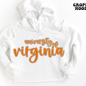 May include: White cropped hoodie with the text "university of virginia" in orange lettering.