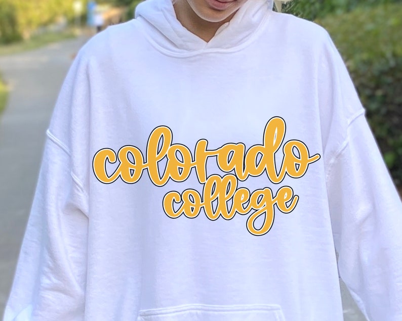 May include: White hoodie with a yellow and black graphic that says "Colorado College" in a handwritten font.