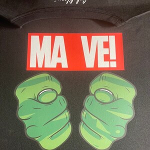 May include: Black t-shirt with a red rectangle that says "MA VE!" and two green fists on either side.
