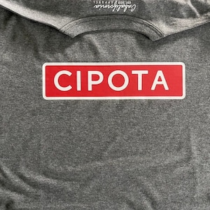 May include: A gray t-shirt with a red rectangular patch that says "CIPOTA" in white letters.