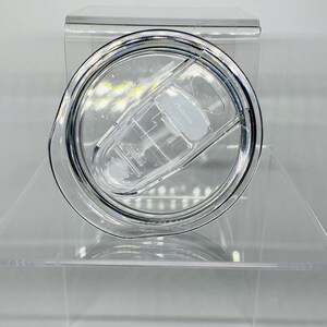 Op de afbeelding: Een doorzichtig plastic deksel voor een beker met een drukdeksel. Het deksel heeft een doorzichtige plastic ring rond de rand en een doorzichtige plastic knop in het midden.