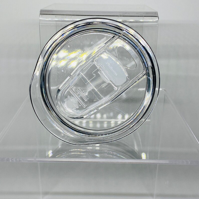 Op de afbeelding: Een doorzichtig plastic deksel voor een beker met een drukdeksel. Het deksel heeft een doorzichtige plastic ring rond de rand en een doorzichtige plastic knop in het midden.