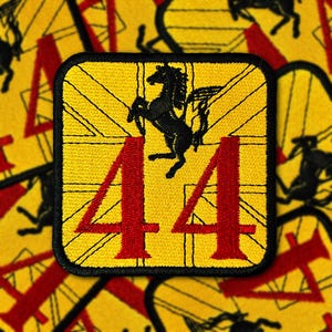 Op de afbeelding: Gele vierkante patch met een zwart paardembleem, rood nummer 44 en een Union Jack-ontwerp. De patch heeft een zwarte rand, waarschijnlijk een logo.