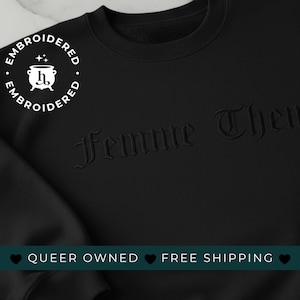 Könnte beinhalten: Schwarzes Sweatshirt mit dem gestickten Schriftzug "Femme Them" in gotischer Schrift. Ein weißes kreisförmiges Logo mit dem Wort "Embroidered" umgibt eine Kesselgrafik. Das Sweatshirt hat eine schwarze Farbe.