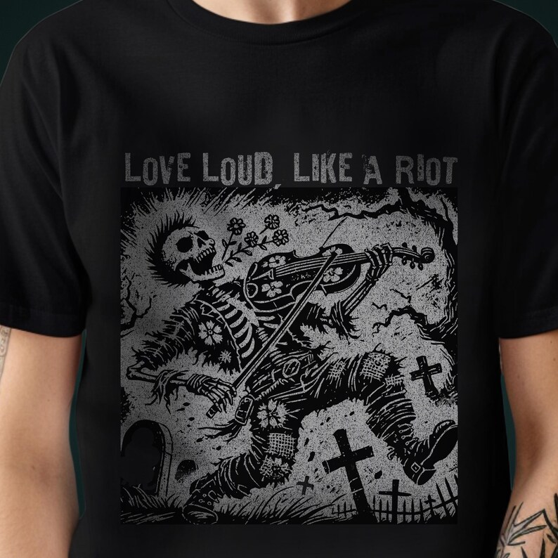 A Folk Punk Linocut shirt with a black and white image of a crust punk Skeleton playing the fiddle in a graveyard. These Offensive T-Shirts have the words Love Loud, Like A Riot; at the top.