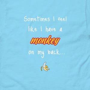 Puede incluir: Camiseta azul claro con texto blanco que dice "Sometimes I feel like I have a monkey on my back..." y un gráfico de cáscara de plátano amarillo.