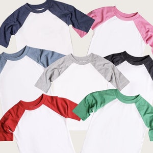 May include: Six different color baseball t-shirts with white sleeves and white bodies. The colors are red, green, blue, grey, pink, and black.