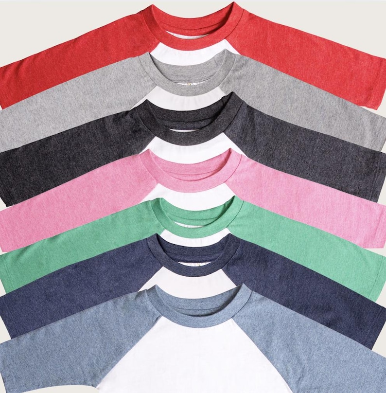 May include: A collection of raglan baseball shirts in various colors, including red, gray, black, pink, green, and blue. Each shirt has a white body and colored sleeves. The shirts are arranged in a diagonal pattern, showcasing the different color combinations.