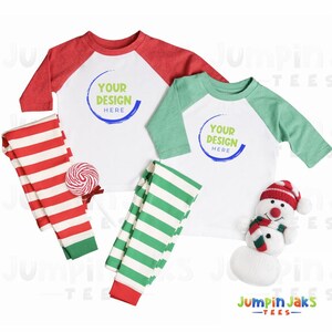 May include: Two raglan sleeve shirts, one red and one green, with the text "YOUR DESIGN HERE". Striped red and green pajama pants and a snowman plushie are also shown. A lollipop is also included.