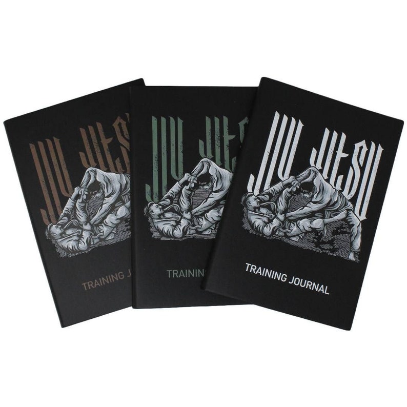 Puede incluir: Tres diarios de entrenamiento negros con el texto "Jiu Jitsu" en blanco y un gr&aacute;fico de dos personas en un combate de jiu jitsu. Los diarios tienen el texto "Training Journal" en la parte inferior.