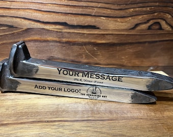 May include: Two metal horseshoe nails with engraved text: "YOUR MESSAGE" and "ADD YOUR LOGO!". The nails are silver with dark gray accents and are displayed on a wooden surface. The text "Pick Your Font" is also visible.