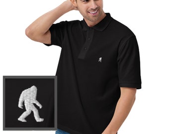 May include: Black short-sleeved polo shirt with a white embroidered Bigfoot design on the left chest.