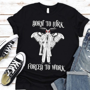 Peut inclure: T-shirt noir avec un papillon blanc portant un costume et le texte "Born to Work, Forced to Work".
