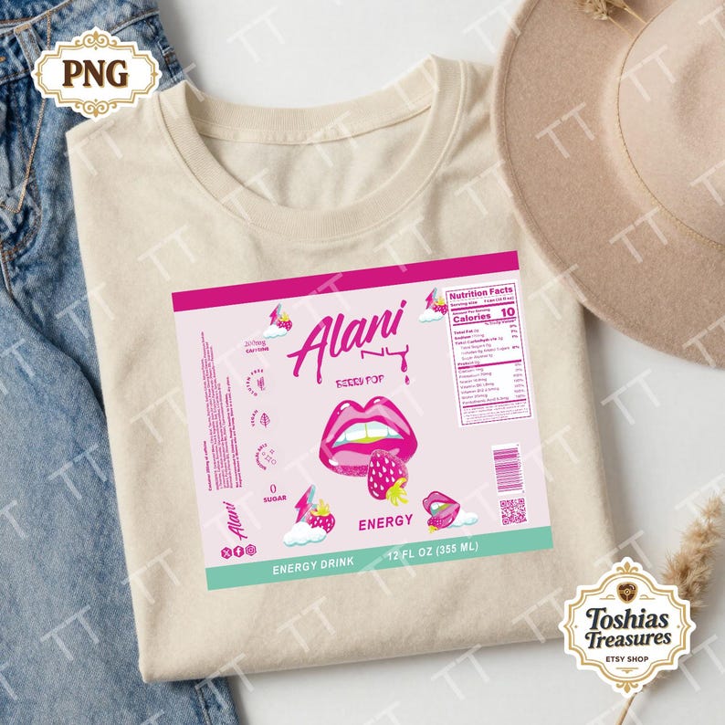 May include: A cream-coloured t-shirt with a pink and white graphic for "Alani NY Energy Drink." The design includes a strawberry, lips, and nutritional information. The shirt is 355 ml.