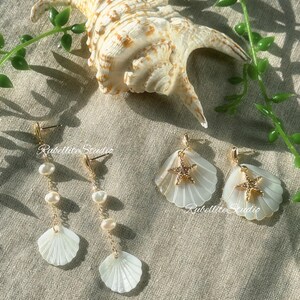 May include: Seashell-themed earrings are displayed. Two pairs have white shell pendants with gold details and a gold starfish. One pair features dangling pearls. A large seashell and greenery are in the background. The text "Rubellitte Studio" is visible.