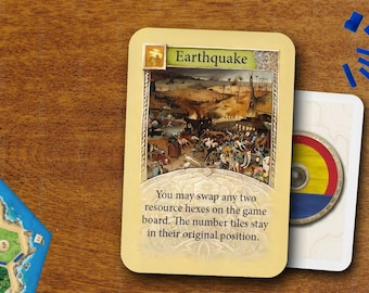 Könnte beinhalten: Eine rechteckige Spielkarte mit dem Titel Earthquake, die eine detaillierte Landschaftsdarstellung und einen Text zum Tausch von zwei Ressourcen-Hexfeldern zeigt. Daneben liegen blaue Kunststoffteile, ein gelber Würfel, ein roter Würfel und ein Spielbrett.