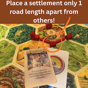 May include: A board game setup featuring hexagonal terrain tiles, red wooden settlement pieces, and a game card labeled Neighbours. The text reads: Place a settlement only 1 road length apart from others! and You may place one settlement within only one road length from another settlement.