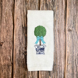Peut inclure: Serviette de toilette blanche avec un motif brodé d'un arbre en forme de boule vert dans un pot bleu et blanc avec un nœud bleu.